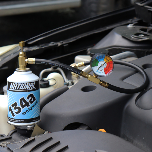 1 Can of R-134a refrigerant attached to a charging hose sitting in an engine bay